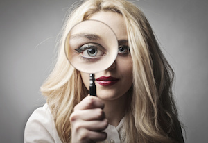 woman holding magnifying glass to her eye