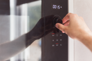 what are membrane switches and uses, Person pressing membrane switch buttons on a microwave control panel showing consumer electronics application