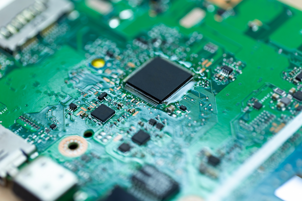 Close-up of a green printed circuit board with microchip and surface-mount components